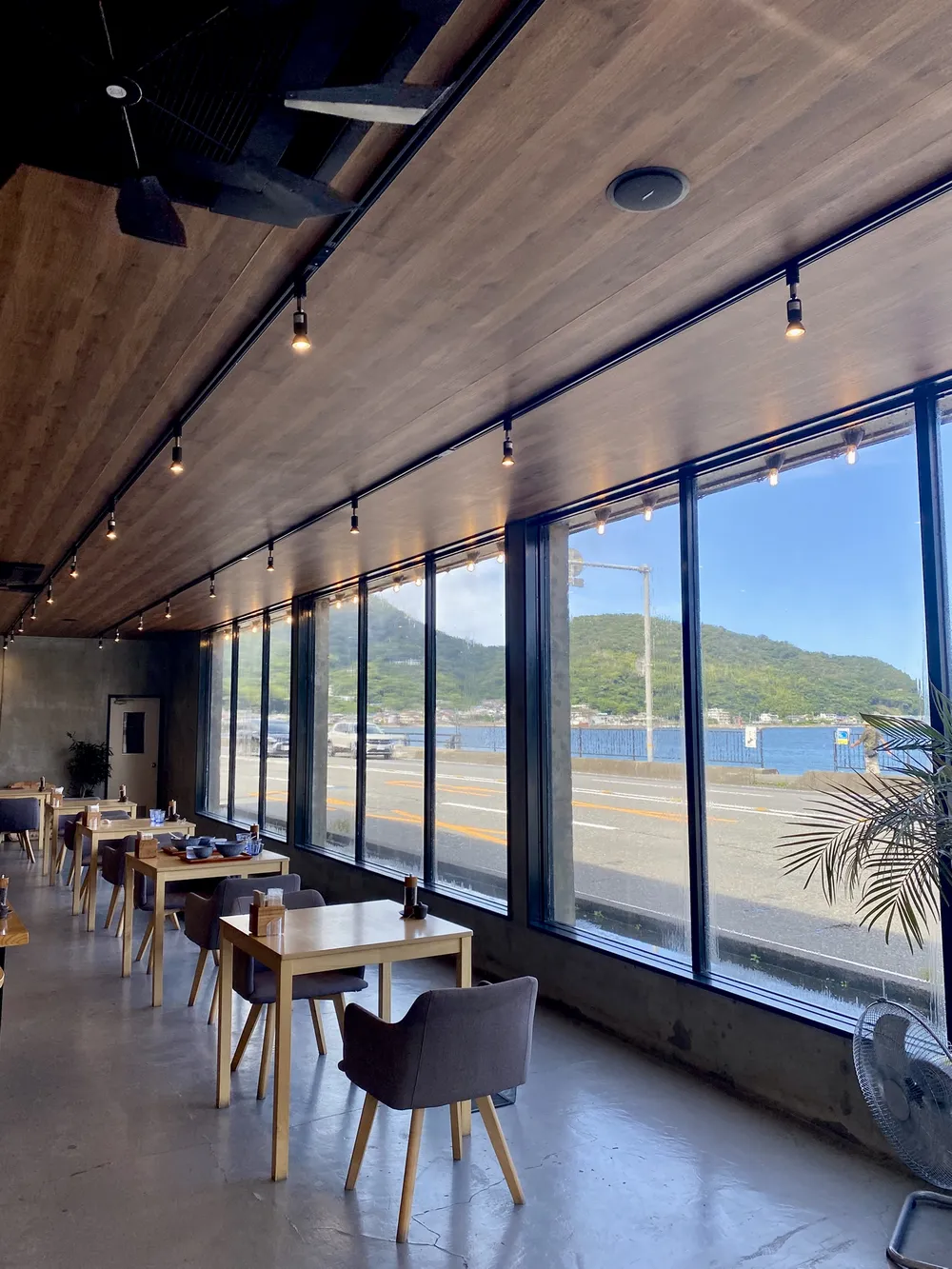 Intérieur du Ramen Village Cafe à Usami avec vue sur la mer depuis les grandes baies vitrées